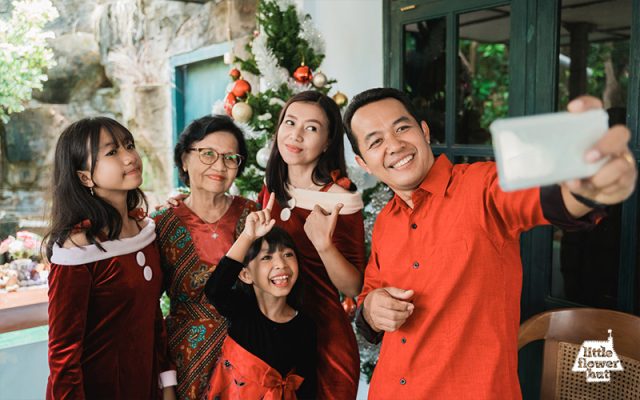 A family of five taking a selfie wearing a Christmas outfit