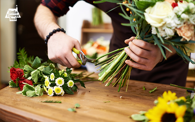 A florist trimming the stem of a bouquet of flowers