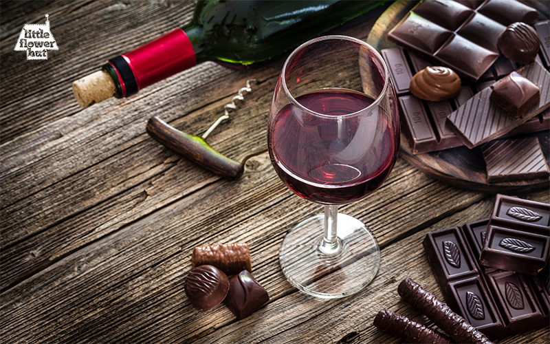 A glass of wine with some chocolates 
