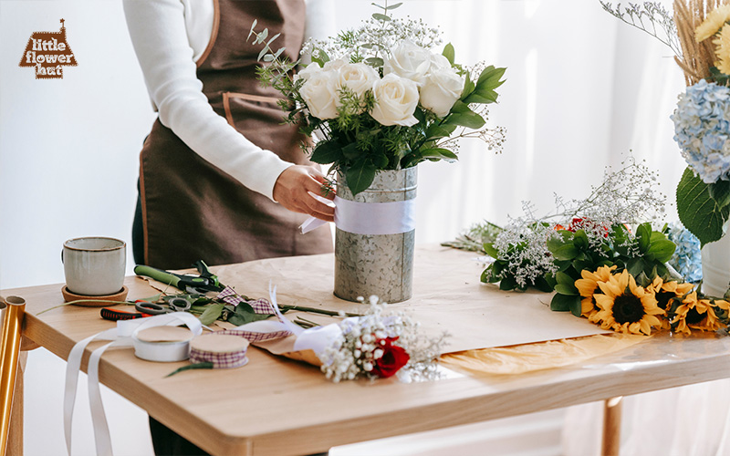 Florist arranging white roses in a vase on a table