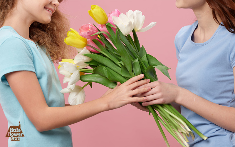 Girl passing a tulip bouquet to her friend