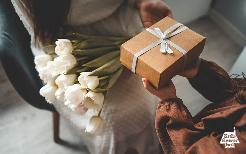 Girl receiving a gift and a white tulip bouquet