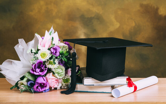 Graduation cap, diploma, and flower bouquet on a table.