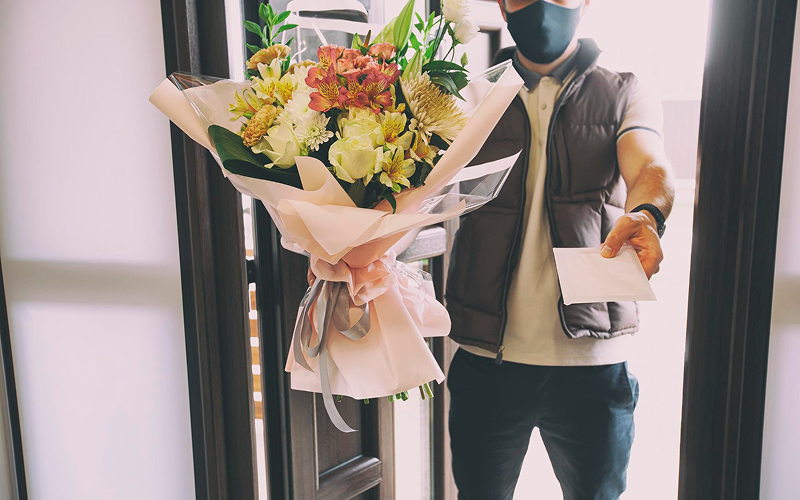 Courier delivering a graduation flower bouquet to a doorstep.